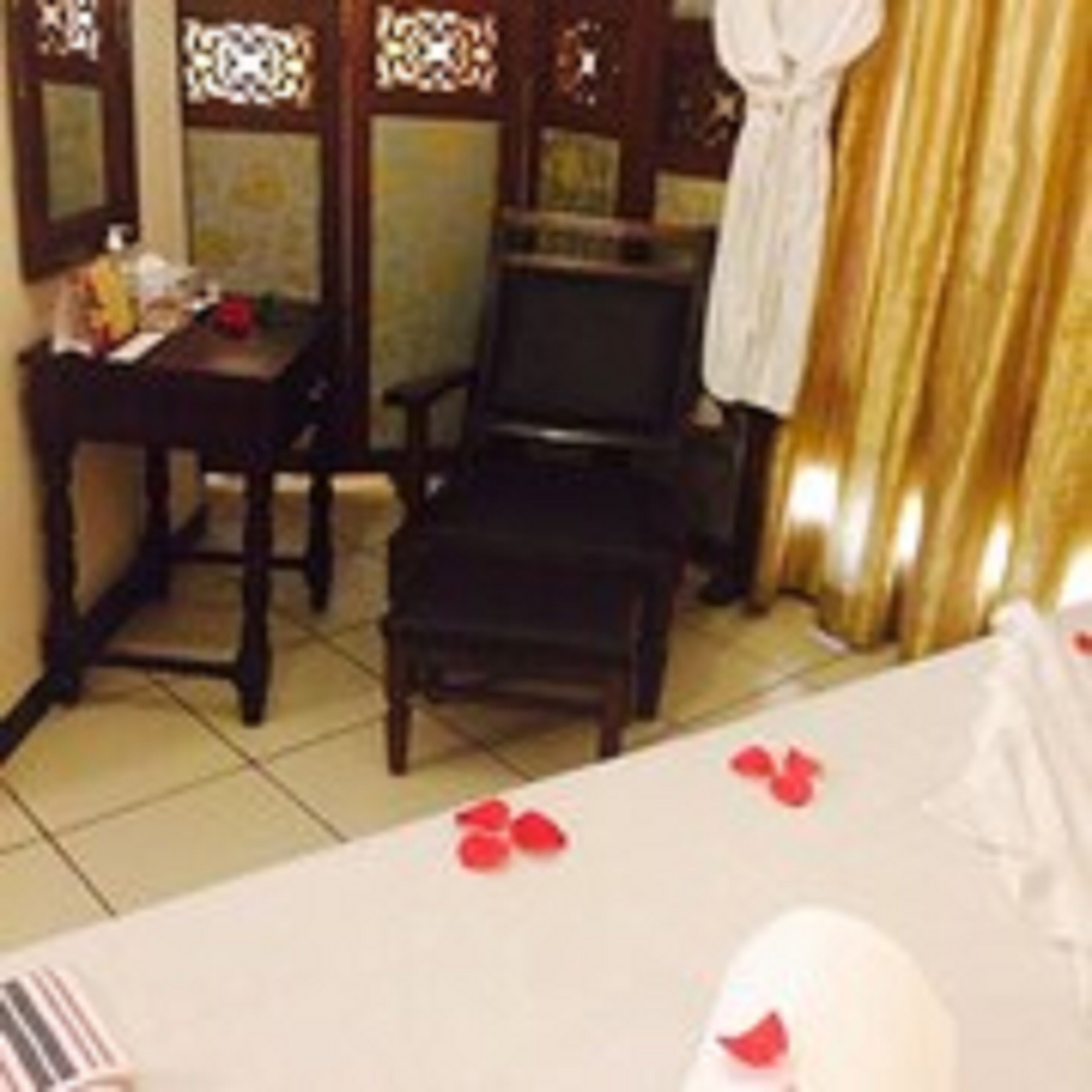Una habitación de hotel con cama, una silla, una mesa y un espejo.