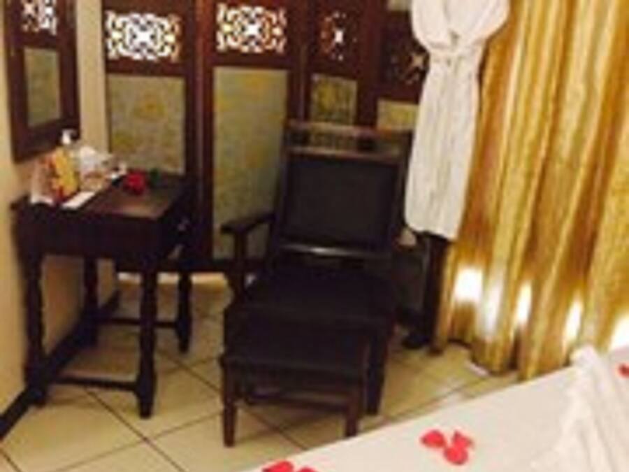 Una habitación de hotel con cama, una silla, una mesa y un espejo.