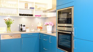 Una cocina moderna con armarios azules, lavavajillas, cafetera y horno doble.