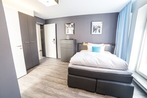 Un dormitorio moderno con una cama, mesitas de noche, un armario y un aparador.