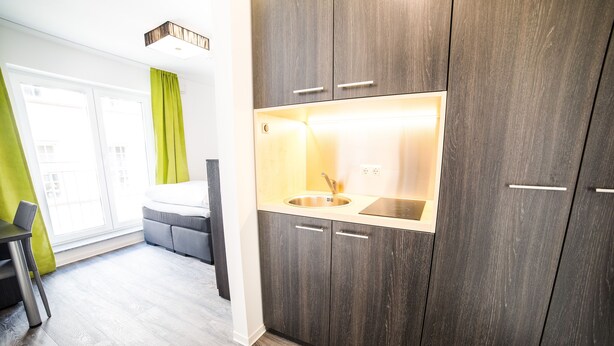 Una cocina moderna con armarios de madera oscura, un lavamanos integrado y una luz de techo brillante.