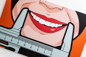 Primer plano de una regla midiendo la sonrisa de una mujer.