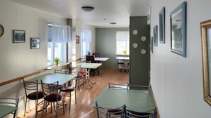 Un espace repas avec plusieurs tables et chaises, une horloge au mur et une fenêtre avec des rideaux.