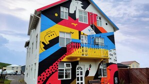 Un bâtiment à deux étages, doté d’une façade aux couleurs vives, d’un balcon et d’un petit espace porche.