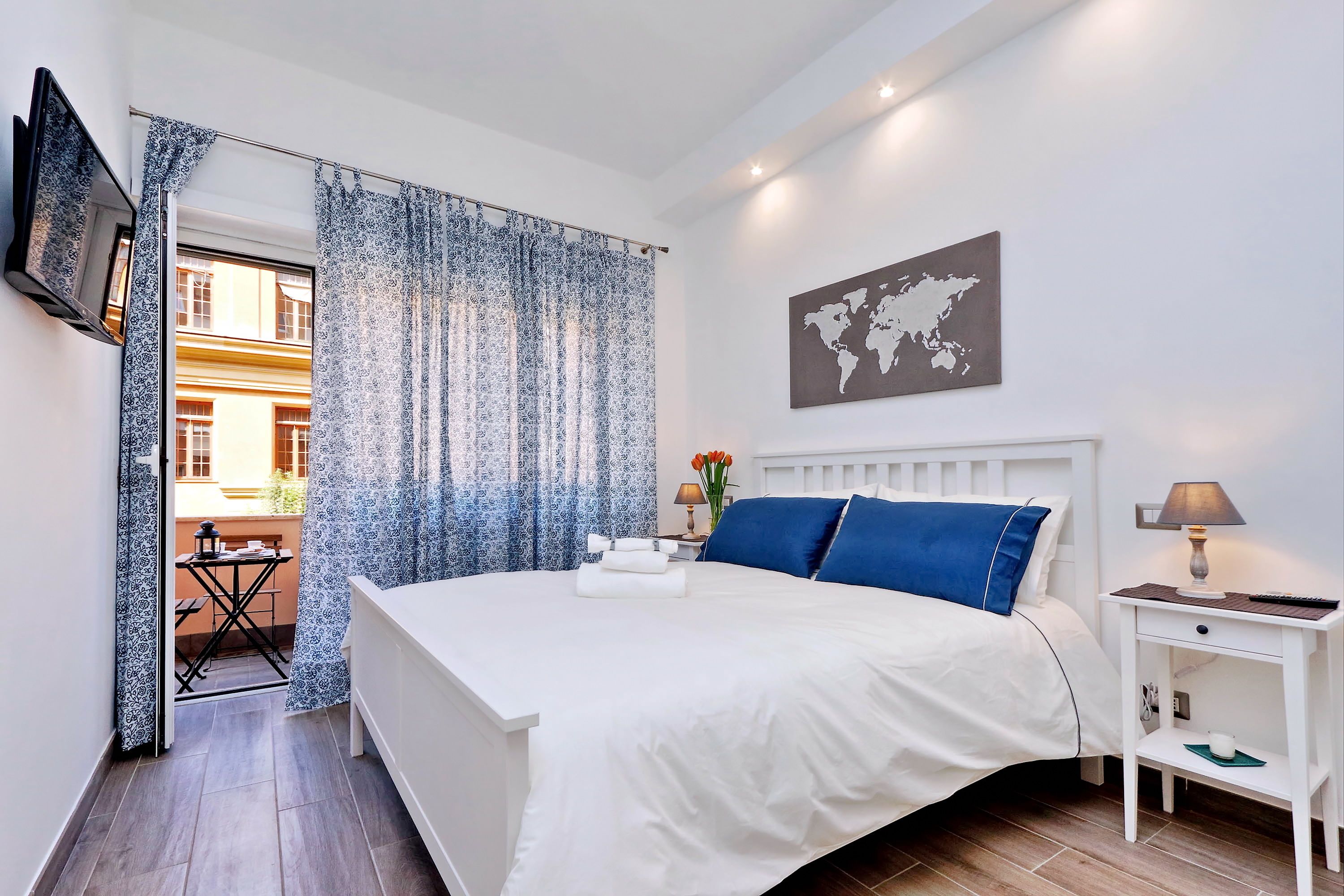 A neatly arranged bedroom with a bed, bedside table, and a world map on the wall.