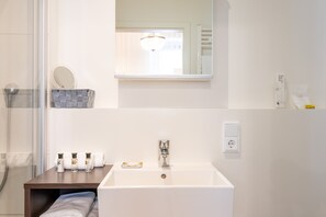 A bathroom with a white sink, a mirror, a towel rack, and a shower.