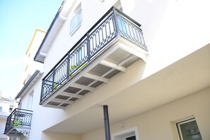 A building with a white facade, a black balcony railing, and a window.
