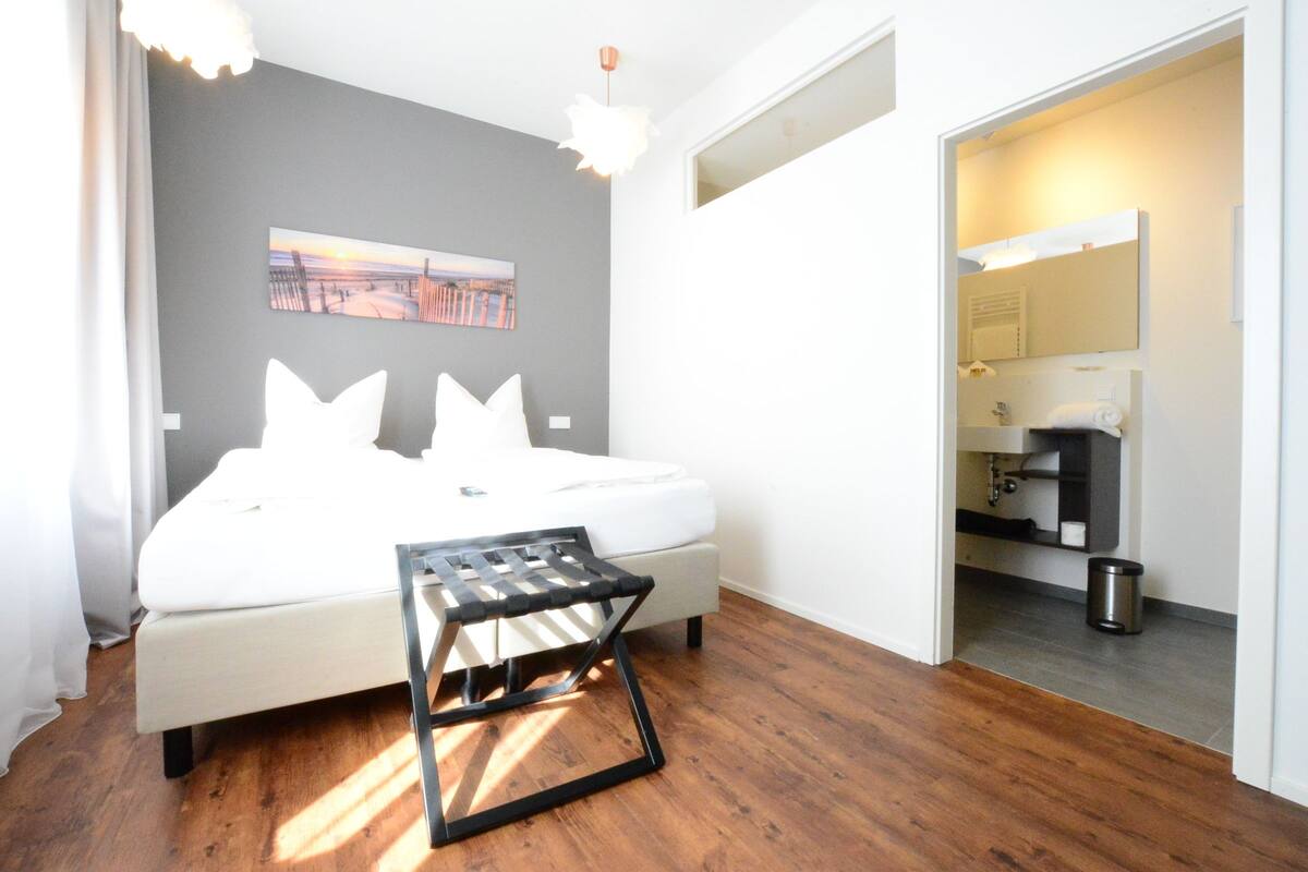 A modern bedroom with a bed, a small table, and a painting on the wall.