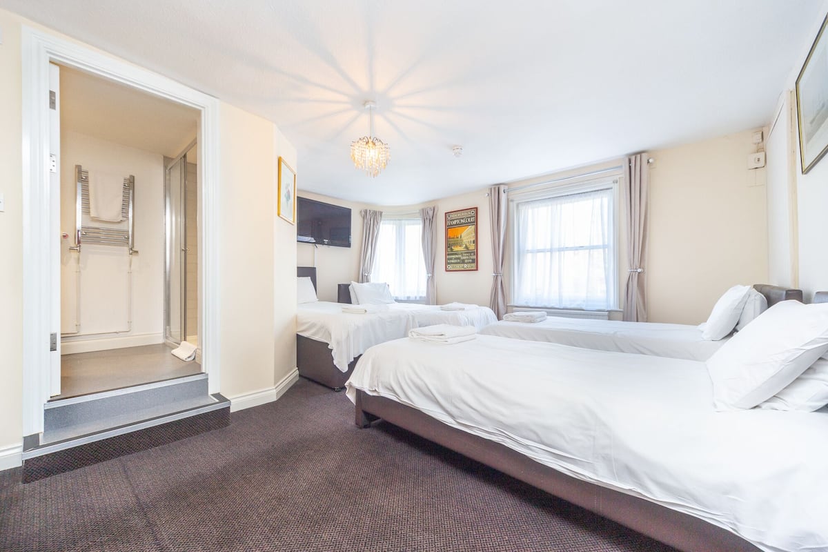 A hotel room with two beds, a shower, a TV, and a poster on the wall.