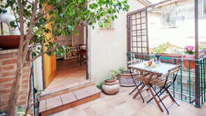 A patio area with a table and chairs, potted plants, and a hanging chair. - Lungaretta 2 - WR Apartments (Rome)