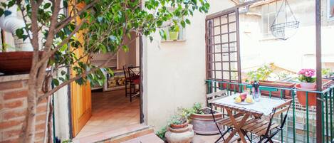 A patio area with a table and chairs, potted plants, and a hanging chair.