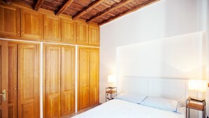 A bedroom with a large bed, wooden wardrobe, and two bedside tables with lamps. - Lungaretta 2 - WR Apartments (Rome)
