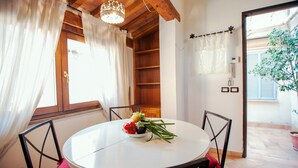A round dining table with chairs, a bowl of fruit, and a potted plant. - Lungaretta 2 - WR Apartments (Rome)