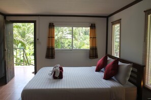 Ein Hotelzimmer mit Bett, Vorhängen und einem Fenster mit Blick auf Grünflächen.