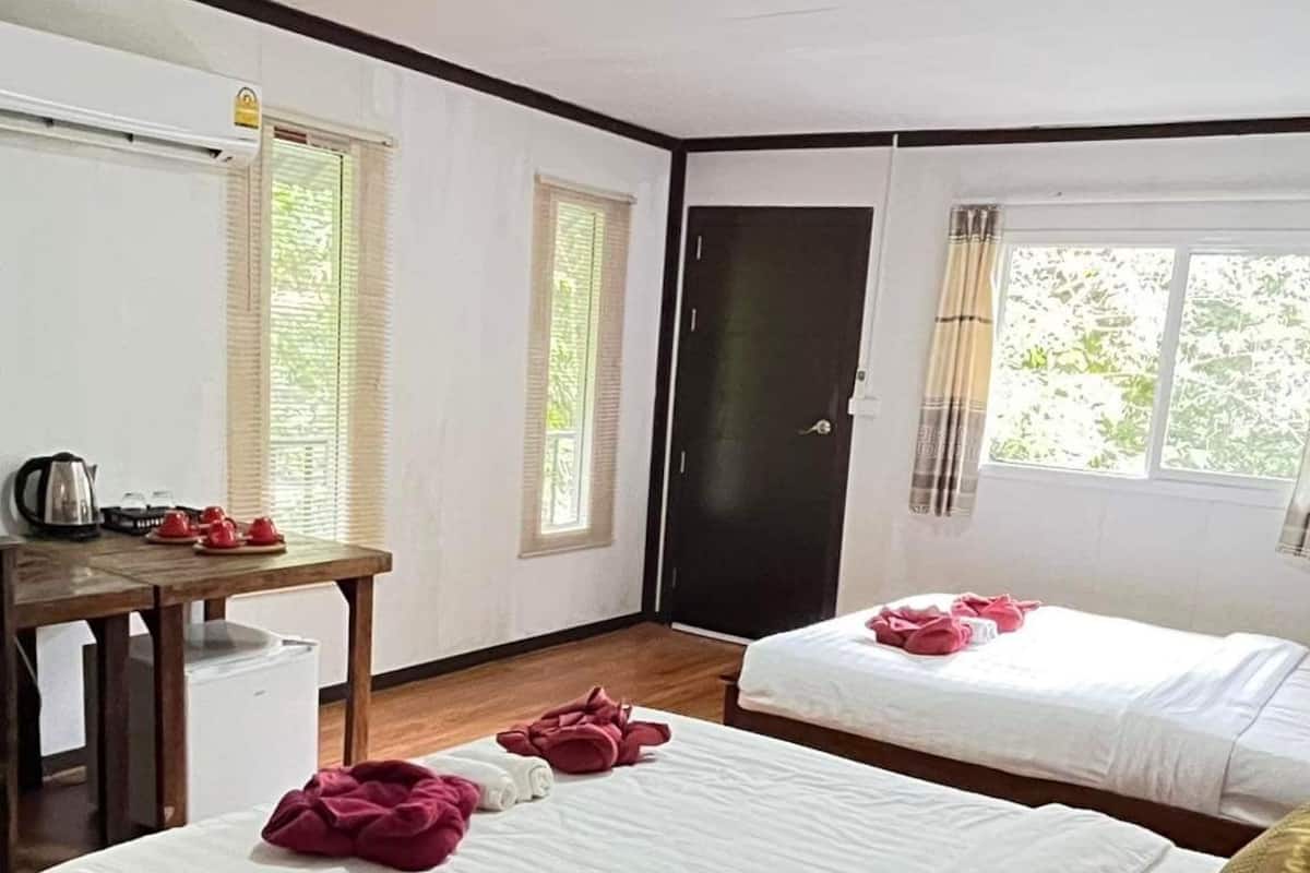 Una habitación de hotel con dos camas, un escritorio con hervidor y una ventana con cortinas.