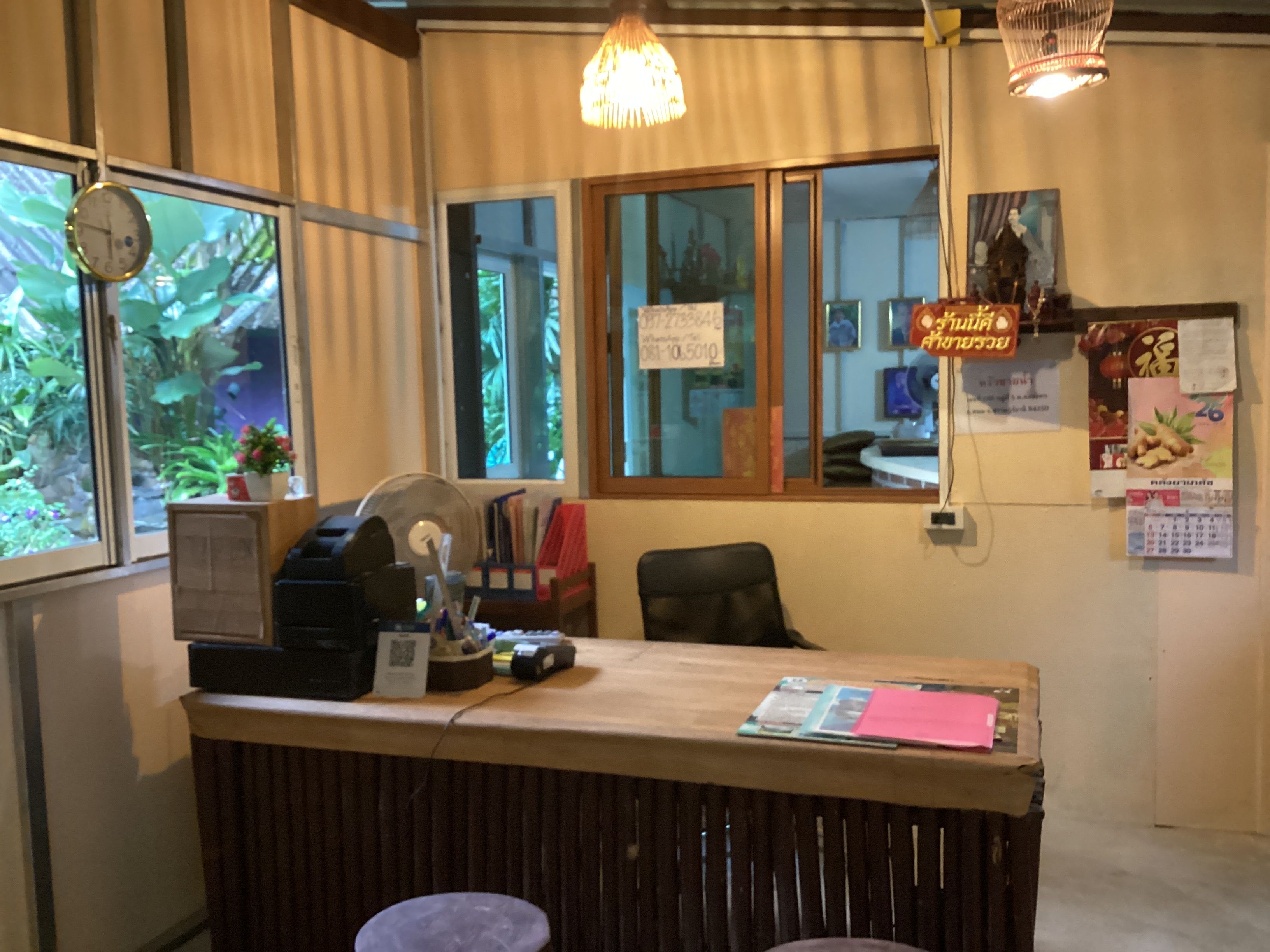 A reception desk with a clock, a fan, and various papers and notices on the wall.