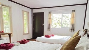 Habitación de hotel con dos camas, suelo de madera, una puerta y ventanas con cortinas.