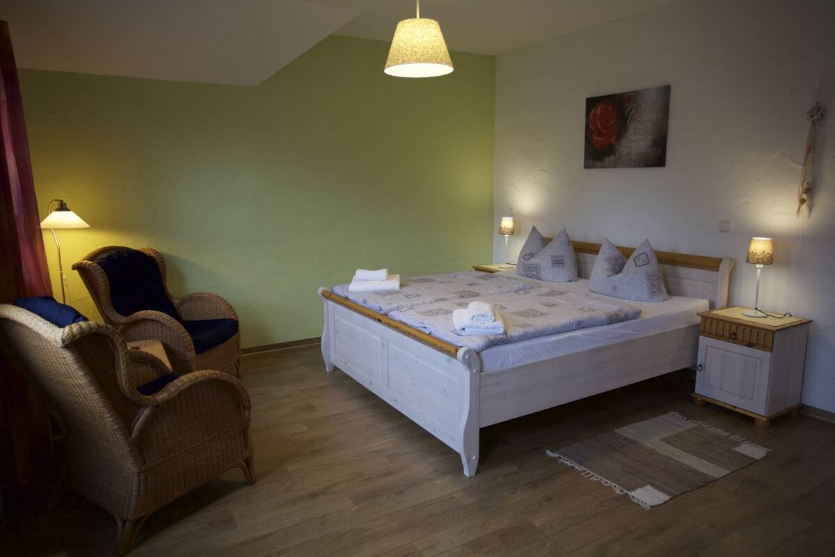 Ein Schlafzimmer mit einem Bett, zwei Stühlen, einem Nachttisch und zwei Wandleuchten.