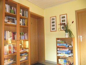 Una habitación con dos estanterías de madera llenas de libros, una puerta y una pared decorada con cuadros.