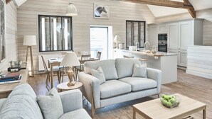 A spacious living area with a sofa, a coffee table, and a dining table. There is a kitchen area with cabinets and appliances. - Chesters Stables (Hexham)