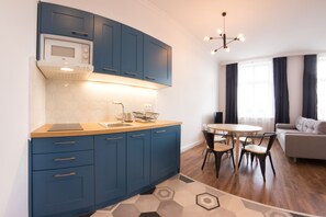 A modern kitchen with blue cabinets, a microwave, and a dining area with a round table and chairs.
