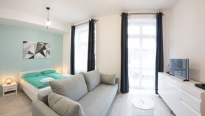Een moderne slaapkamer met een bed, een bank, een televisie en een kleine tafel.