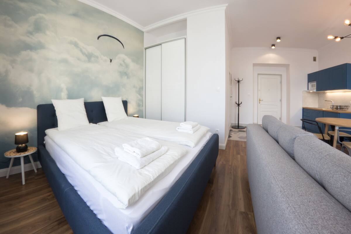 Quarto moderno com uma cama grande, um sofá, área de jantar e um porta-roupas.