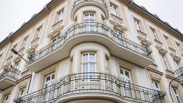Een meerlaags gebouw met een gebogen balkon en meerdere ramen.
