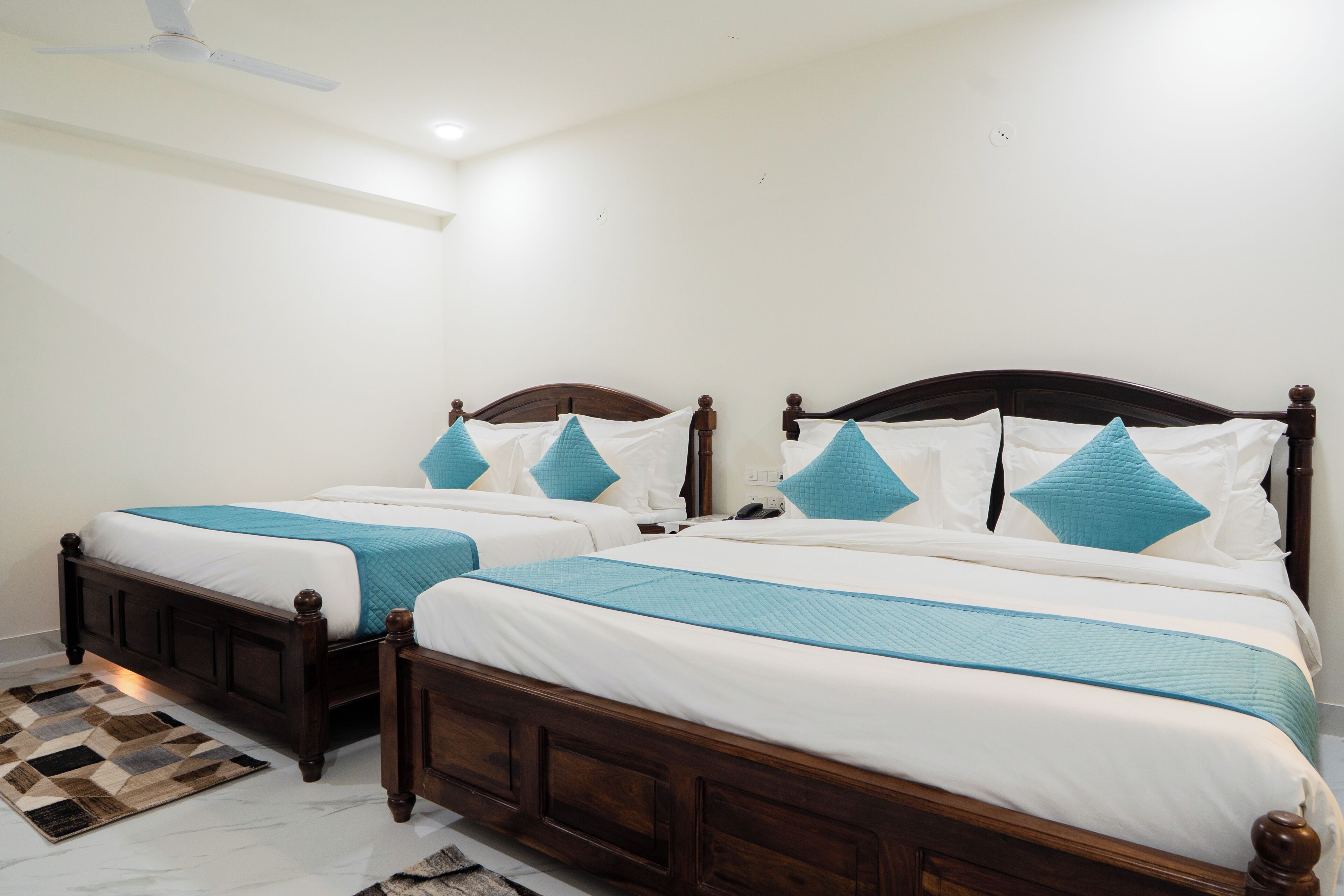 Une chambre à coucher avec deux lits en bois, une literie blanche et des touches de couleur turquoise.