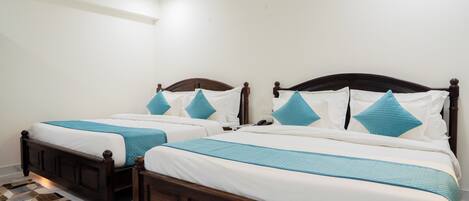 Une chambre à coucher avec deux lits en bois, une literie blanche et des touches de couleur turquoise.