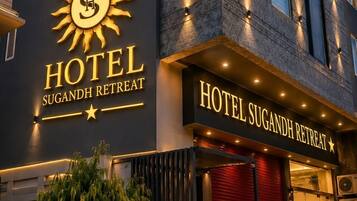 Un hotel con un llamativo logo de sol y el nombre 'Hotel Sugandh Retreat' en la fachada.