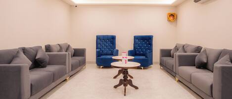 A modern living room with two grey sofas, a blue armchair, and a small round table.