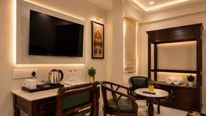 Habitació d'hotel amb televisió de pantalla plana, un quadre, escriptori amb cafetera, cadires, taula petita i finestra amb vistes.