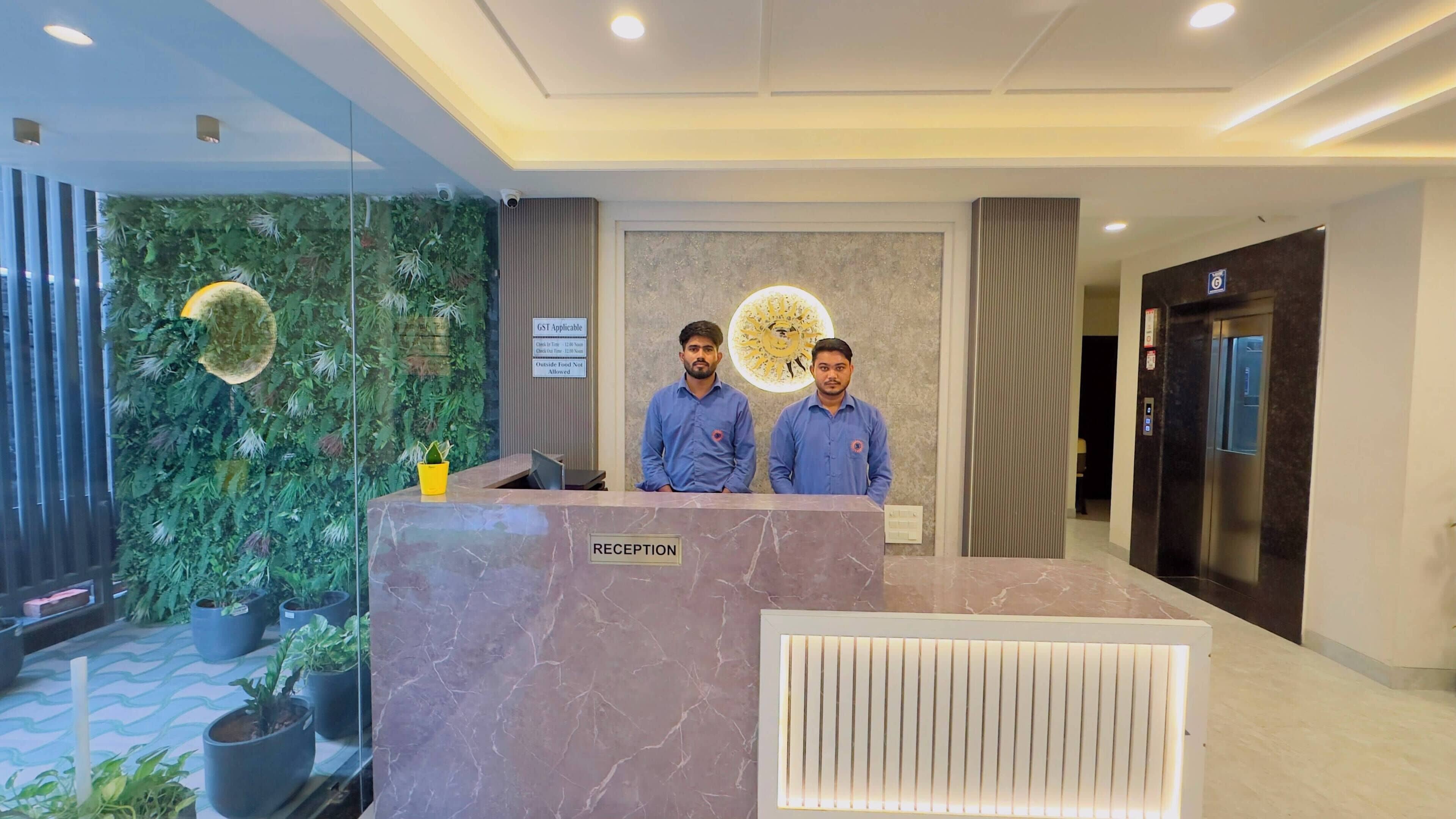 A reception desk with a 'RECEPTION' sign, a wall with a circular design, and a potted plant.