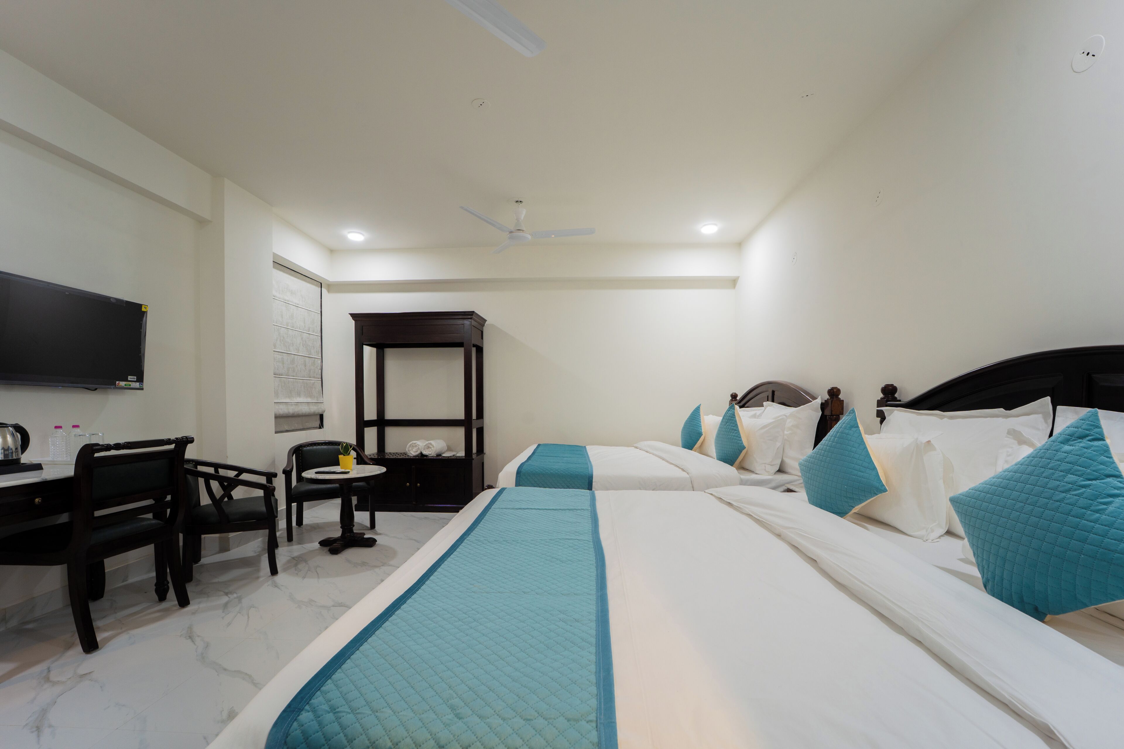 Une chambre d’hôtel équipée d’un lit, d’un bureau, d’une chaise, d’une télévision et d’un ventilateur de plafond.