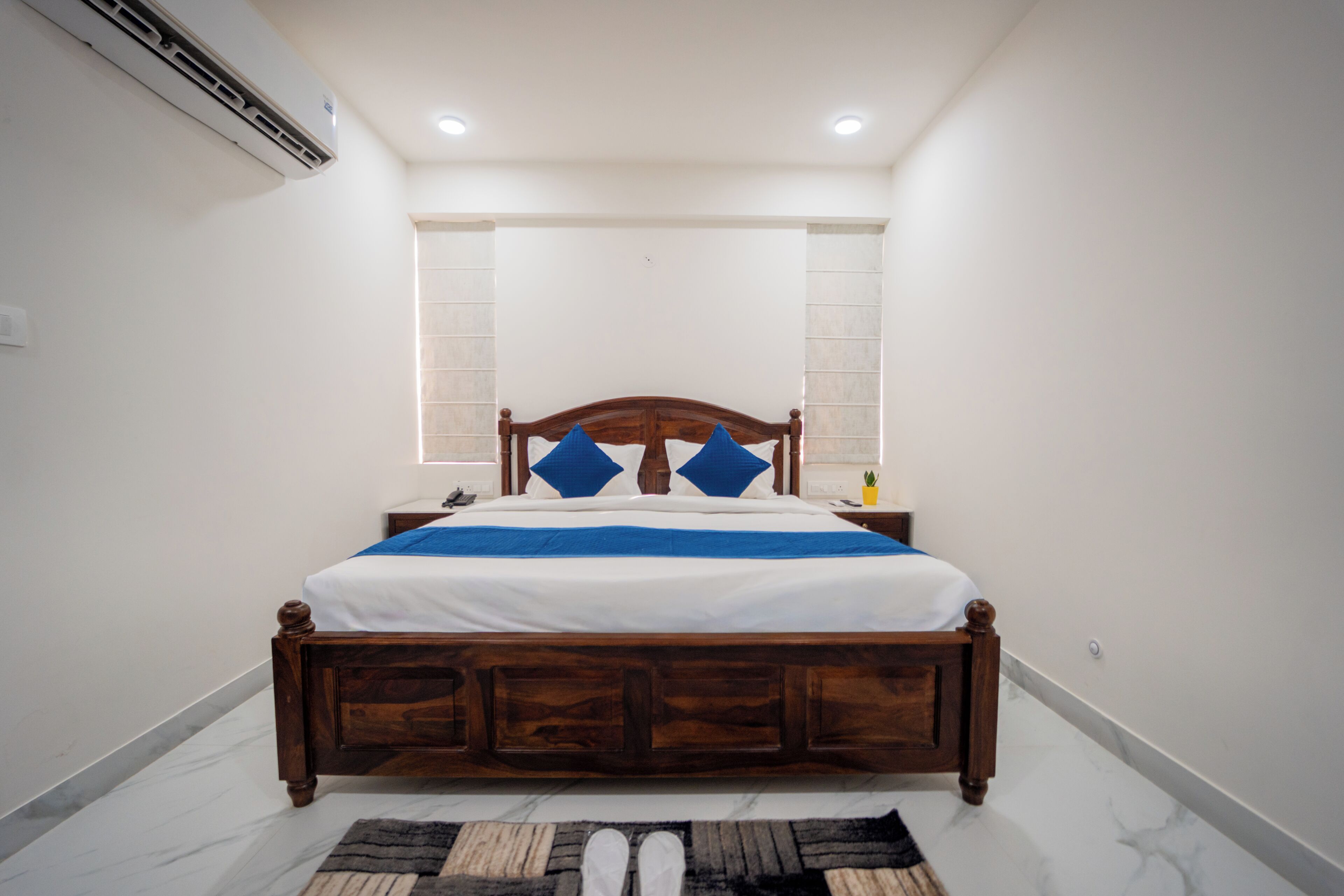 A bedroom with a wooden bed, white walls, and a marble floor.