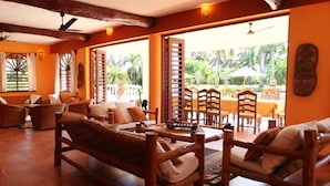 A spacious room with wooden furniture, large windows, and a view of palm trees. - Sunset Villa Resort (Diani Beach)