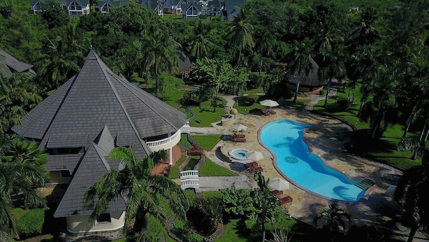 A large house with a swimming pool, surrounded by lush greenery and palm trees. - Sunset Villa Resort (Diani Beach)