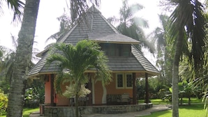 A small, single-story building with a sloped roof, surrounded by palm trees and greenery. - Sunset Villa Resort (Diani Beach)