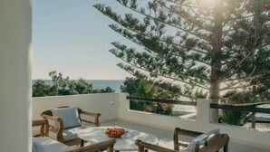 A balcony with a table, chairs, and a bowl of fruit. - Damma Beachfront Luxury Villa (Santorini)