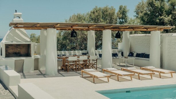A poolside area with a pergola, seating, and a barbecue setup. - Damma Beachfront Luxury Villa (Santorini)