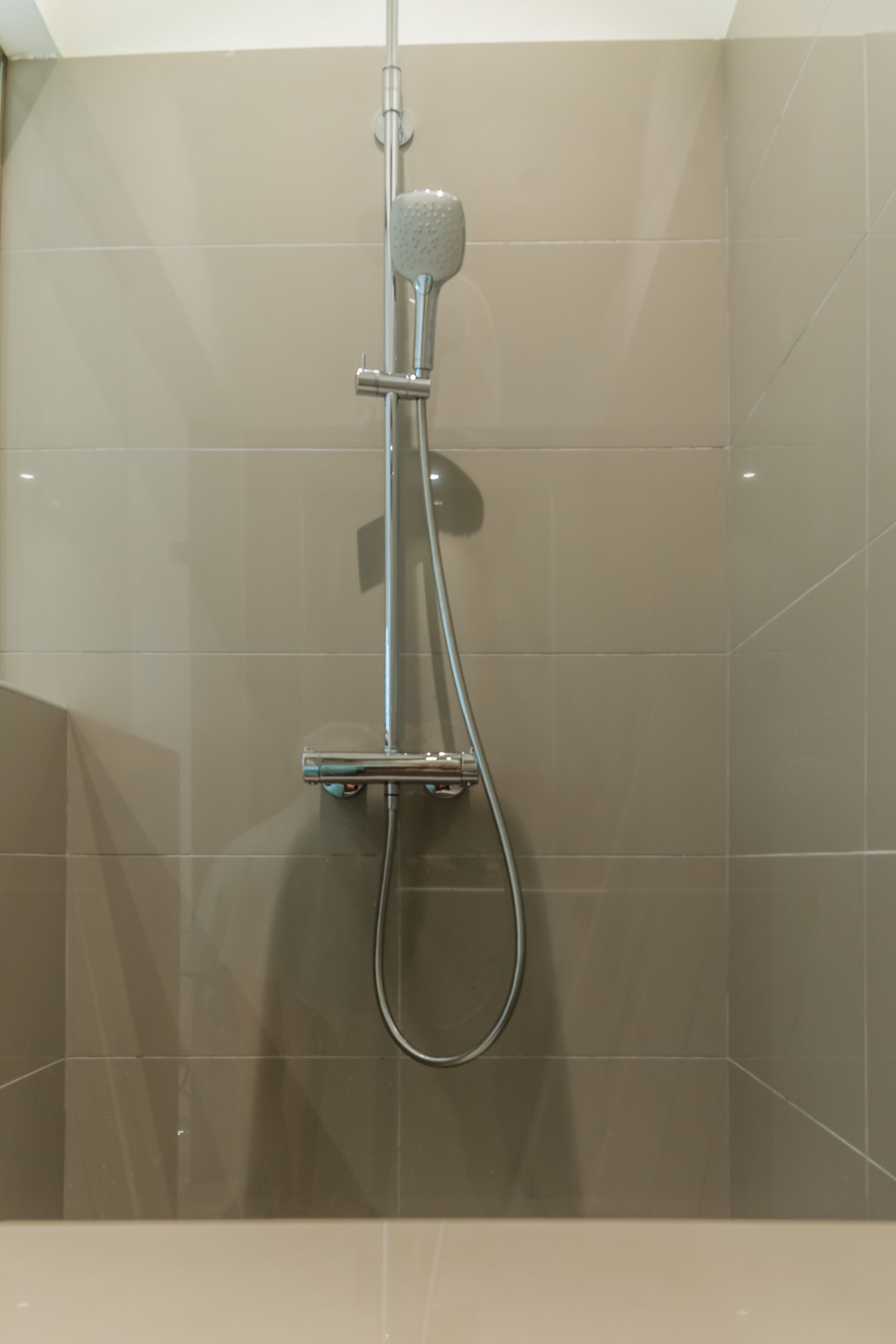 Une douche équipée d’un pommeau de douche à main et d’un panneau de commande fixé au mur.