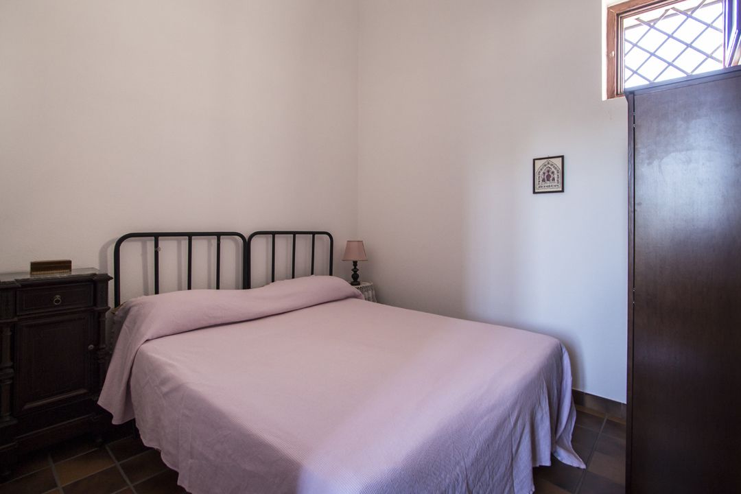 A bedroom with a bed, a nightstand, a lamp, and a wardrobe.