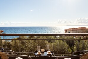 Un balcon avec une table dressée pour deux personnes, offrant une vue sur la côte.