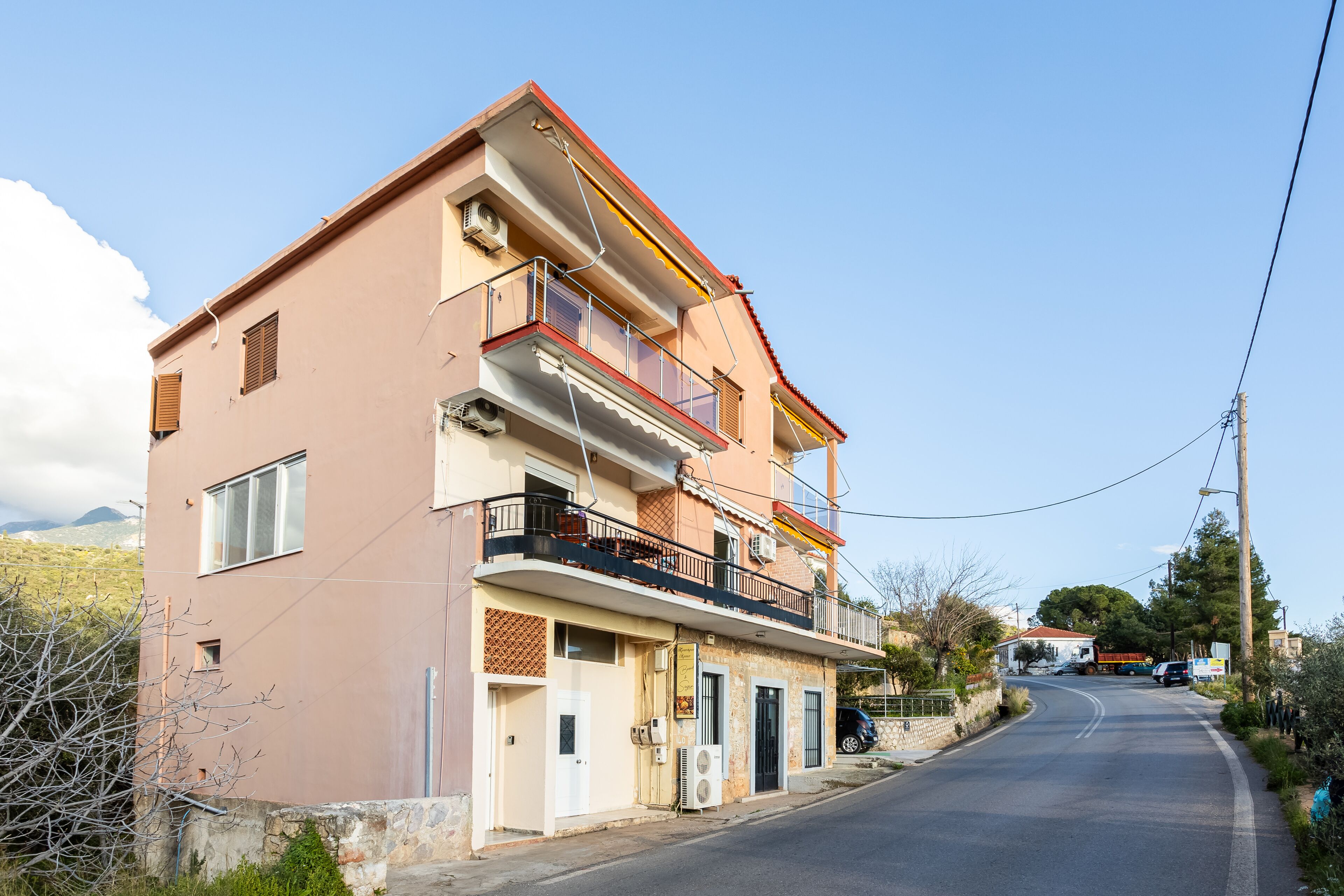 Un immeuble de deux étages doté de balcons, une route devant et un ciel dégagé.