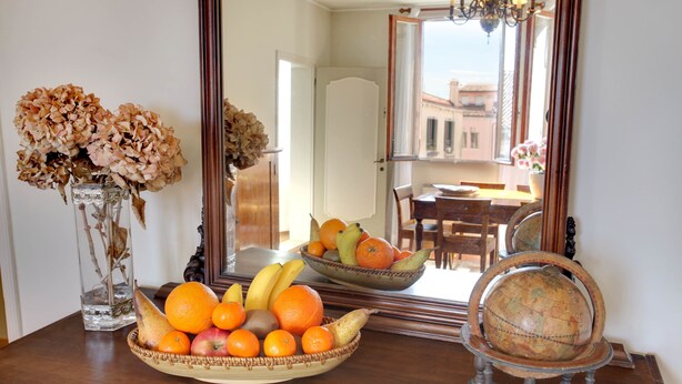 A dining table with a fruit bowl, a vase with dried flowers, and a globe on a stand. - Canale - WR Apartments (Venice)