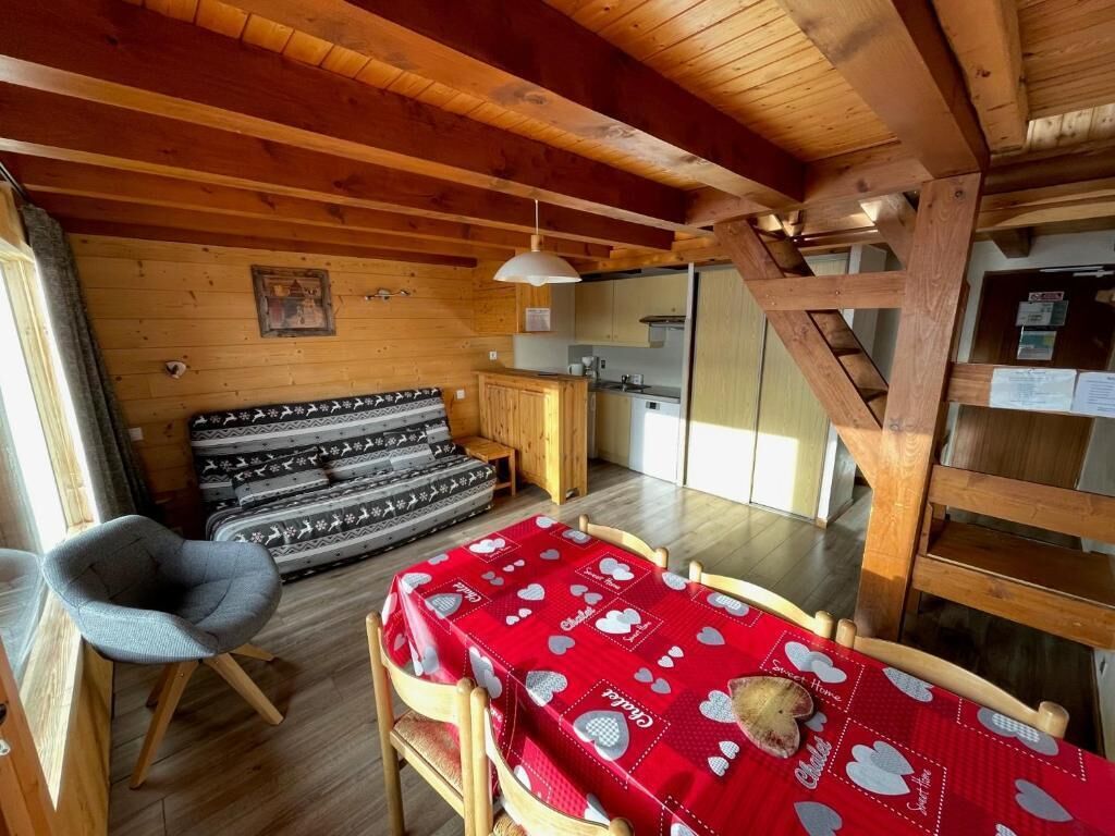 Un interior acogedor de cabaña con comedor, kitchenette y cama con ropa de cama estampada.