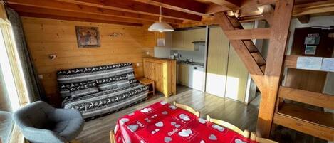 Un interior acogedor de cabaña con comedor, kitchenette y cama con ropa de cama estampada.