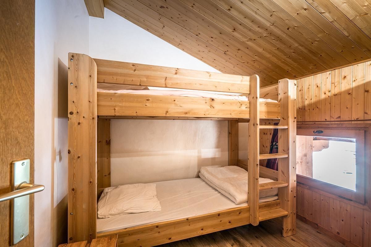 A wooden bunk bed with a ladder, a window, and a door.