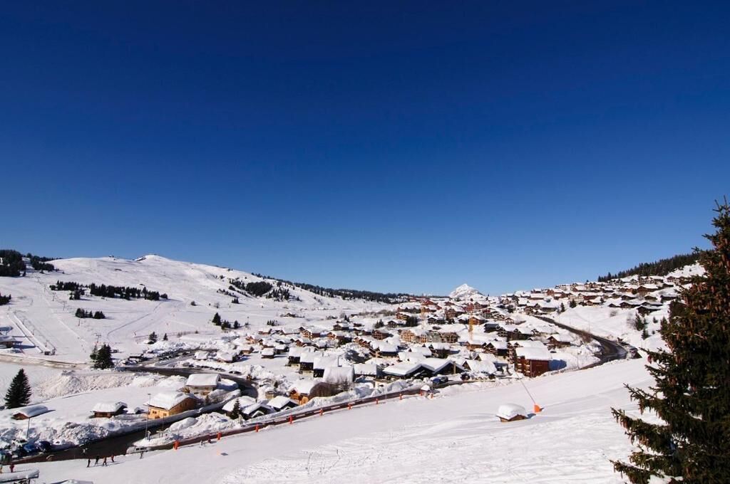 Un village enneigé avec des bâtiments et une piste de ski.